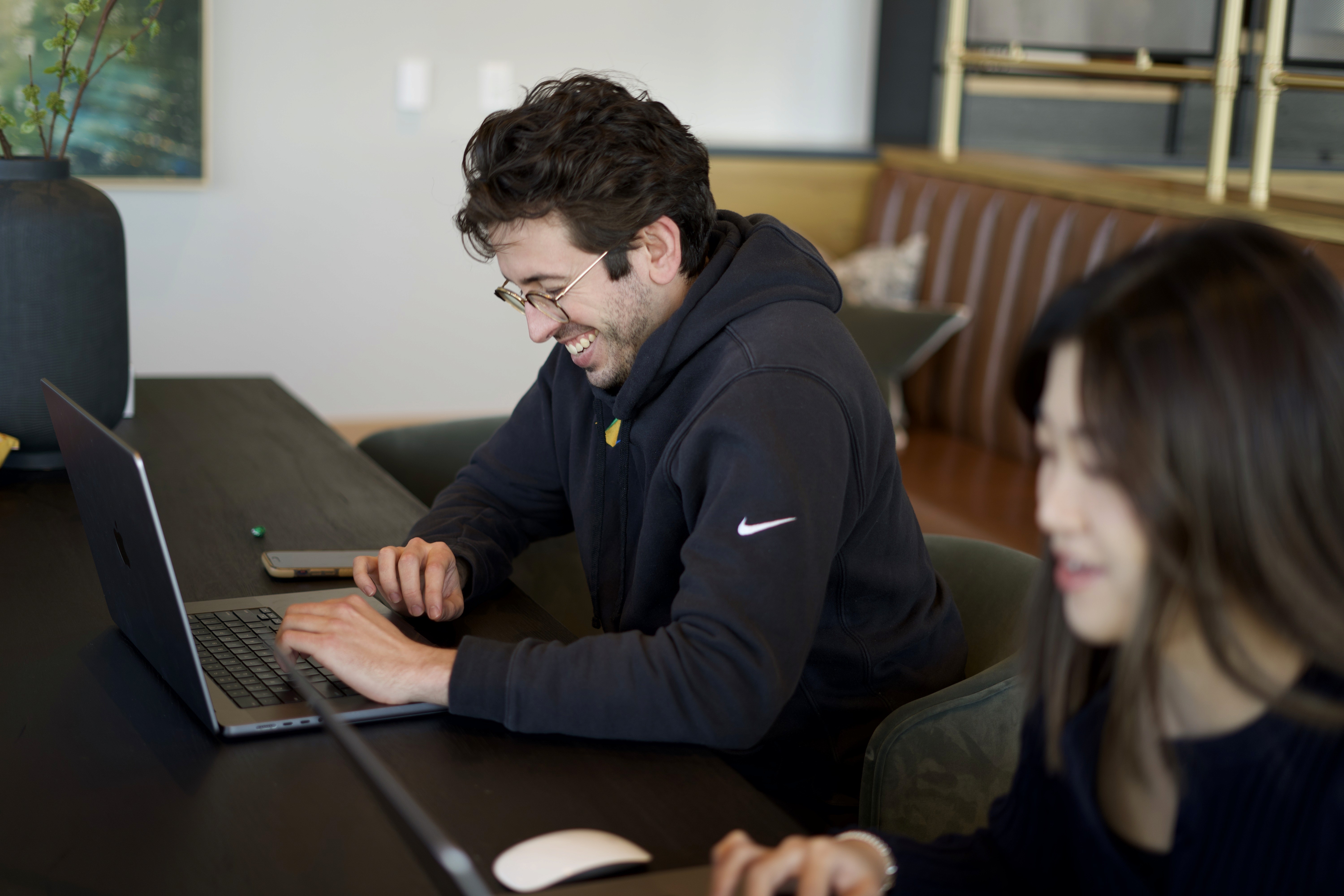 Upstory designers laughing while working on laptops at a shared table